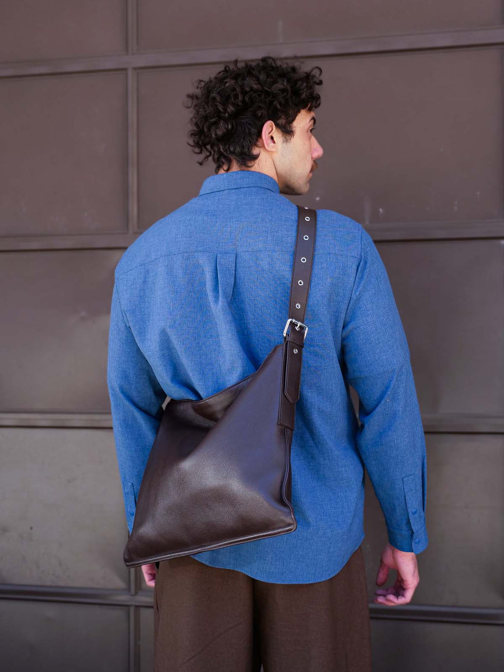 Brown Luxe Kite Bag worn crossbody on the back of a man facing away from the camera