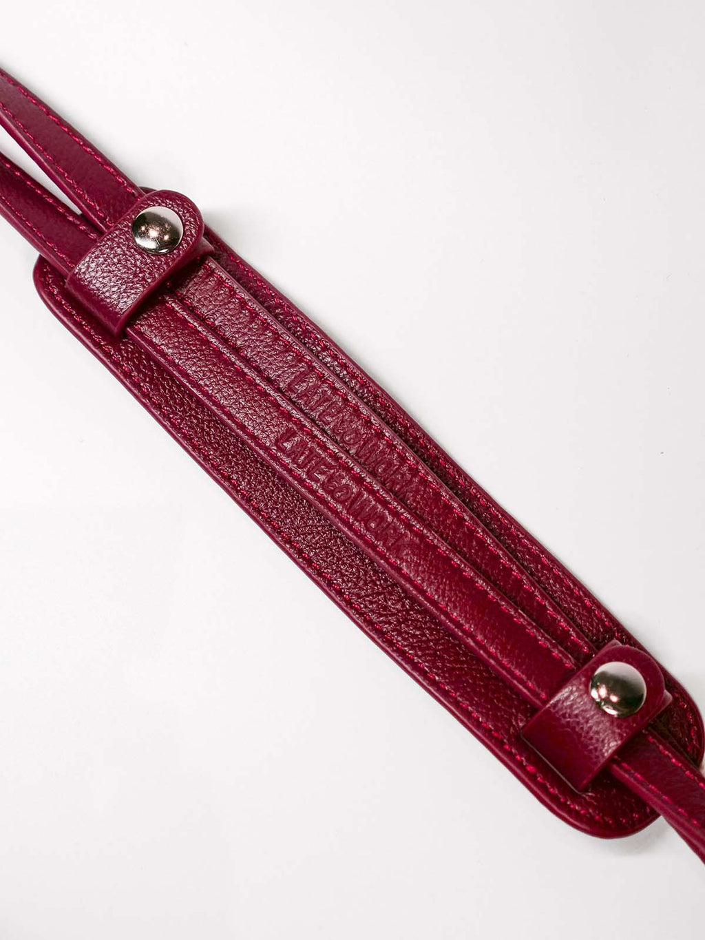 Maroon leather strap with silver hardware on a white background