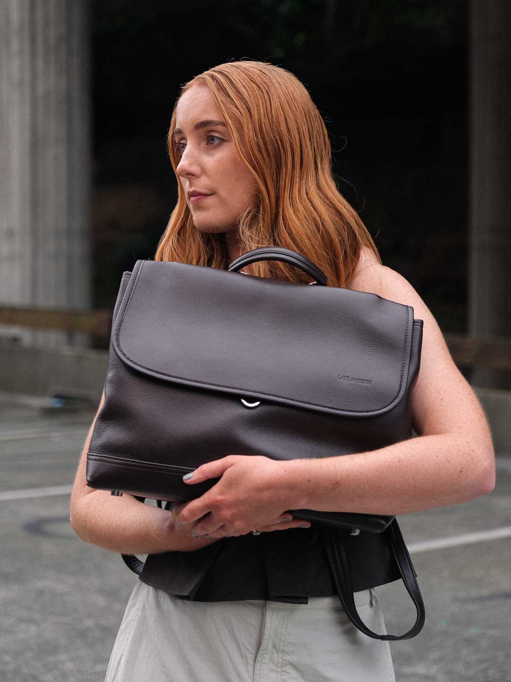 Brown Amari top grain leather backpack cradled by model front view