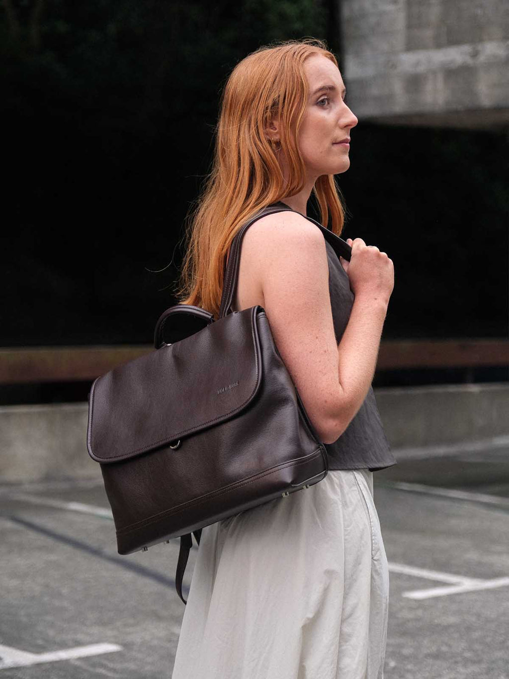 Brown Amari top grain leather backpack worn on one shoulder side view