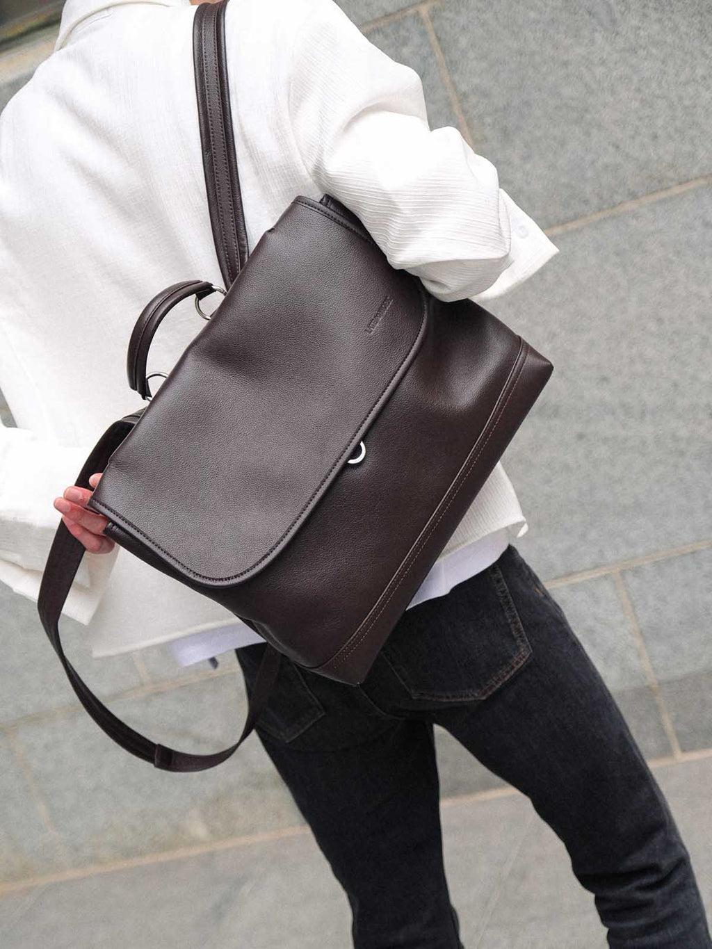 Brown Amari top grain leather backpack worn on one shoulder