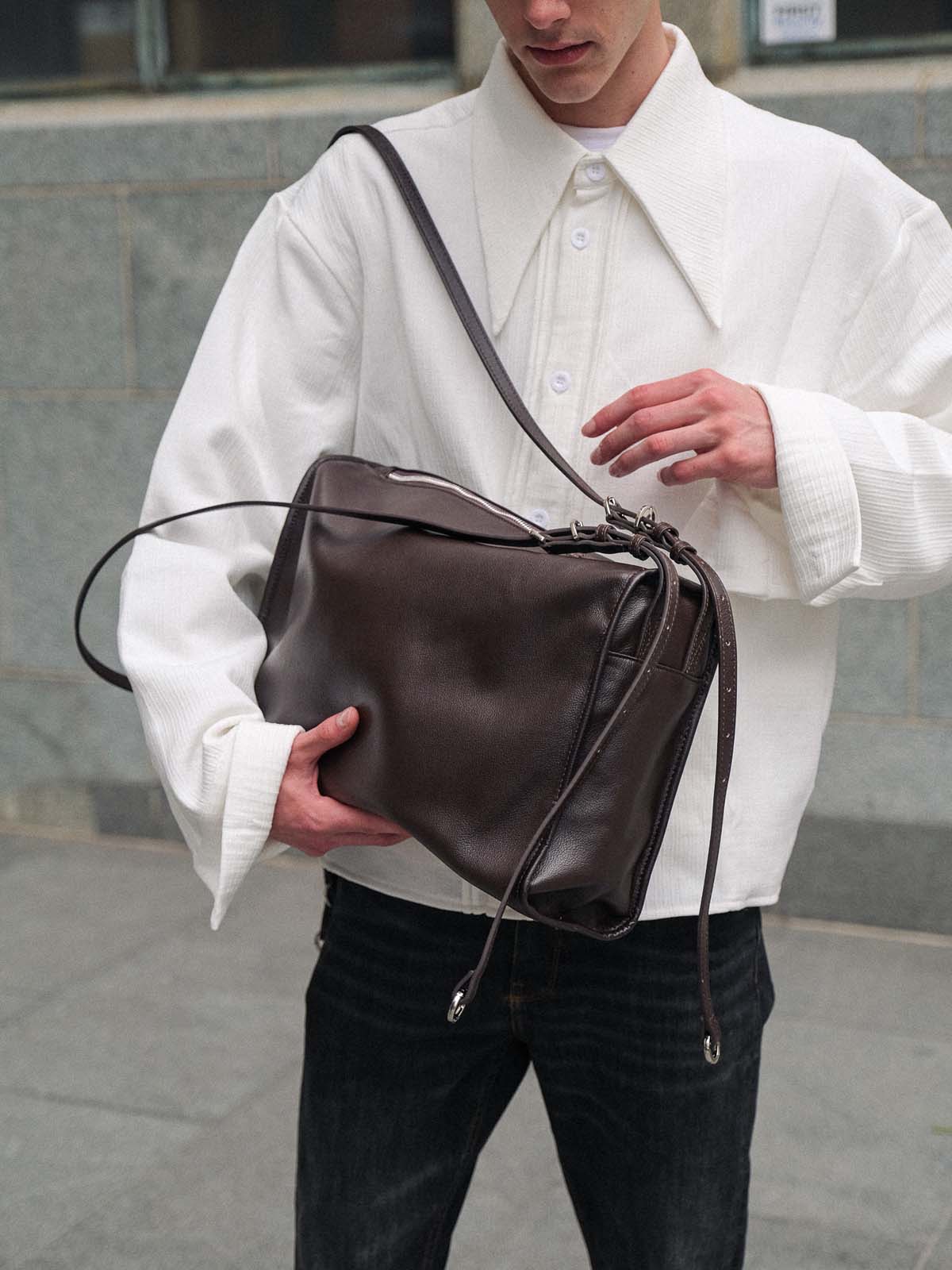 Brown Willow Bag held as a clutch with straps loosely falling off shoulder