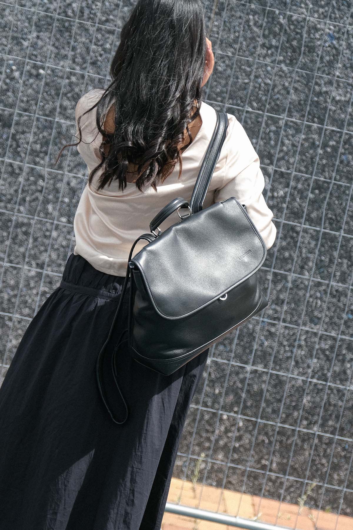 Amari Backpack in black worn on one shoulder from behind