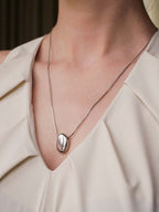Necklace with a pendant worn by a person in a light-colored top.