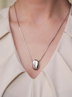 Silver necklace with a pendant on a person wearing a light-colored top.