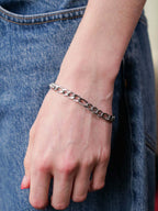 Silver chain bracelet on a wrist with a denim background