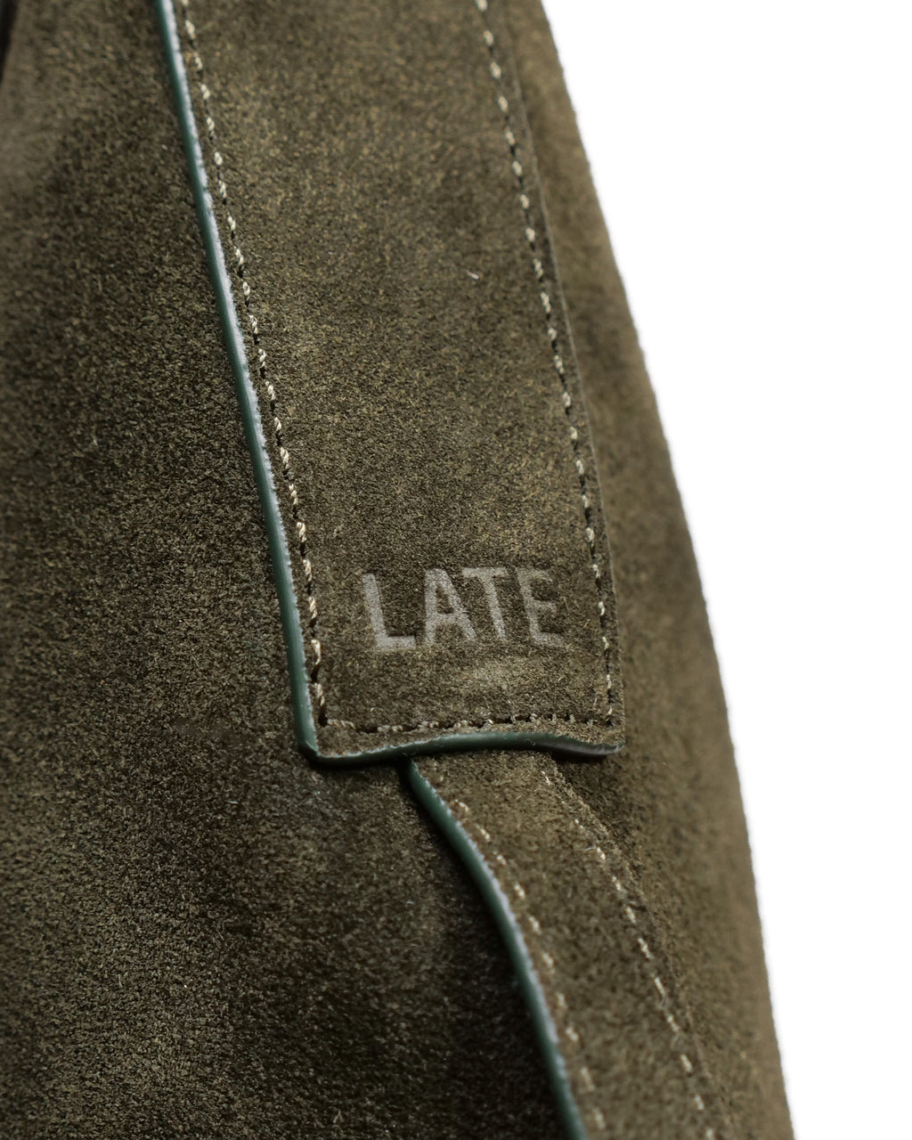 Close up of 'LATE' embossed on green suede