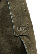 Close up of 'LATE' embossed on green suede