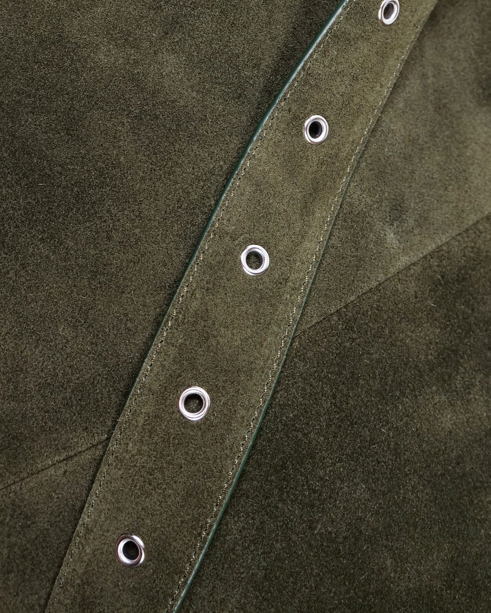 Close up of green suede strap with silver eyelets
