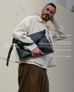 Medium black Kite Bag with product features overlay: premium top grain leather, adjustable strap, 2 interior pockets, fits up to a 13-inch laptop
