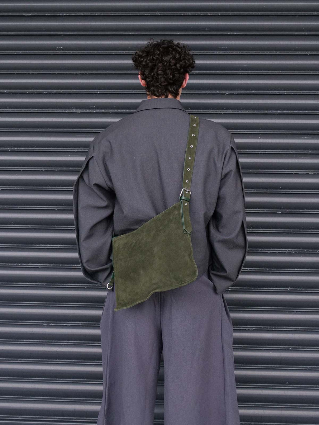 Man facing away from the camera wearing the forest suede medium Kite crossbody on his back