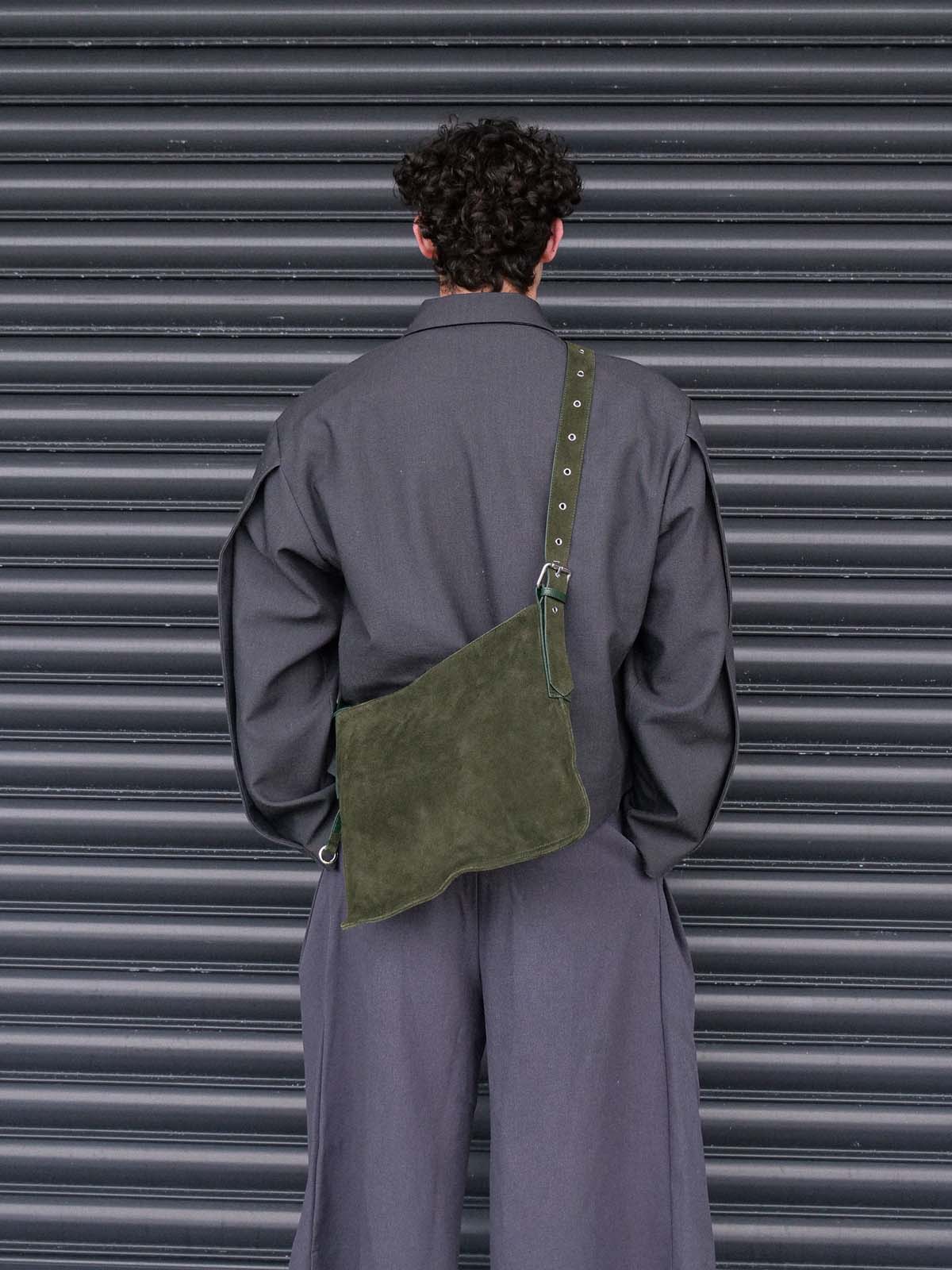 Man facing away from the camera wearing the forest suede medium Kite crossbody on his back