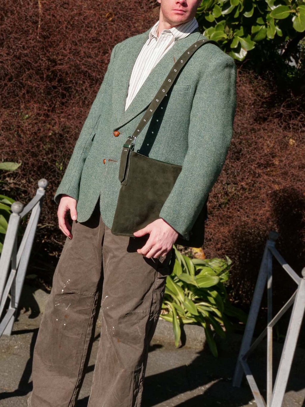 Forest suede Kite Bag worn on one shoulder on a man wearing a green blazer and brown pants