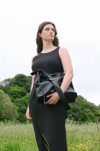 Sage crossbody bag black genuine leather  held by model front view