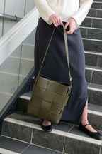Green Marcello Bag held by a model standing on a staircase
