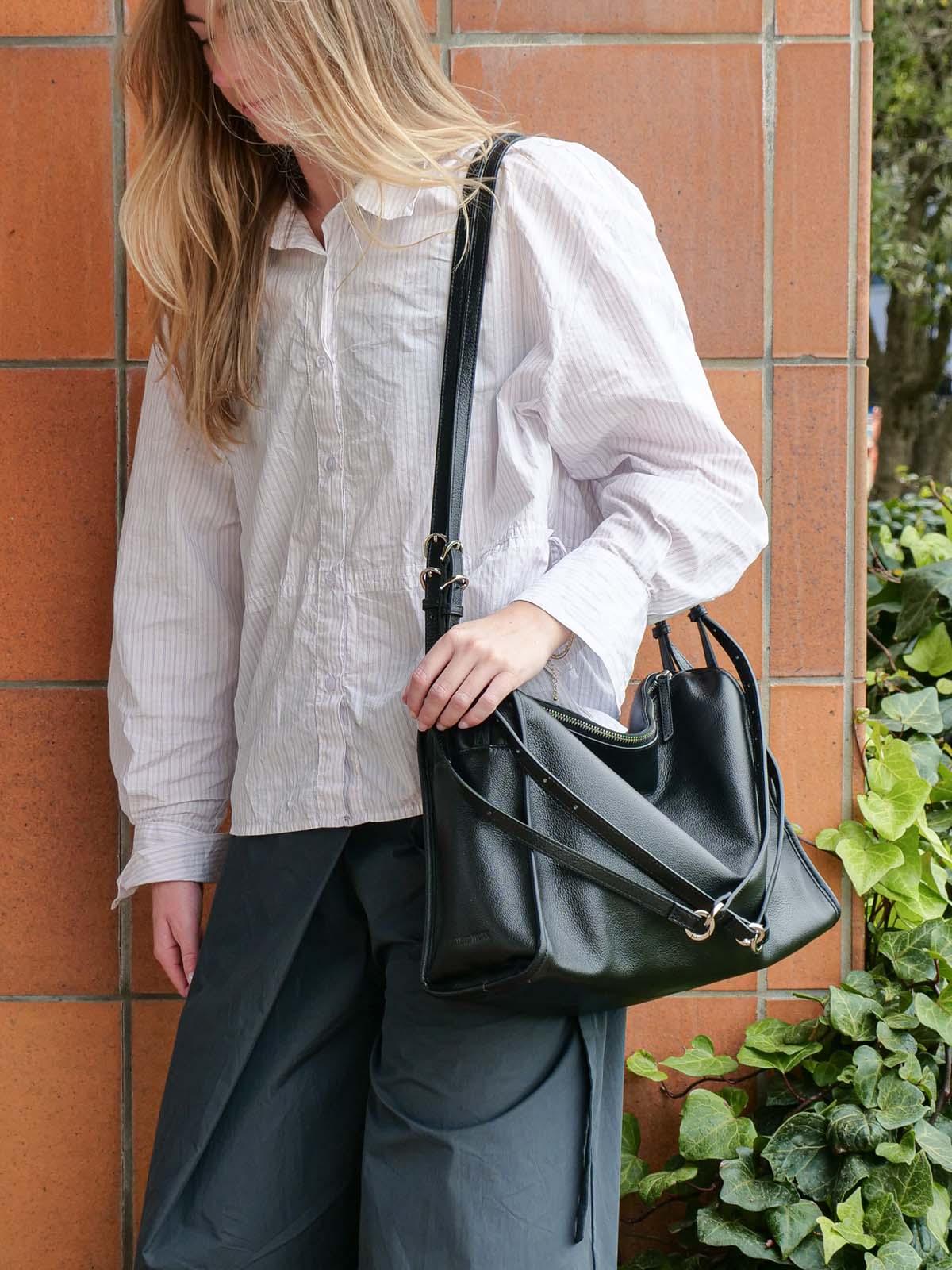 Black Willow Bag worn on one shoulder with all 4 rings attached to each other across the front of the bag