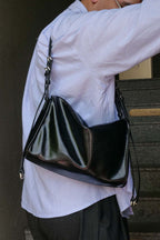 Person wearing a black leather handbag over one shoulder against a neutral background