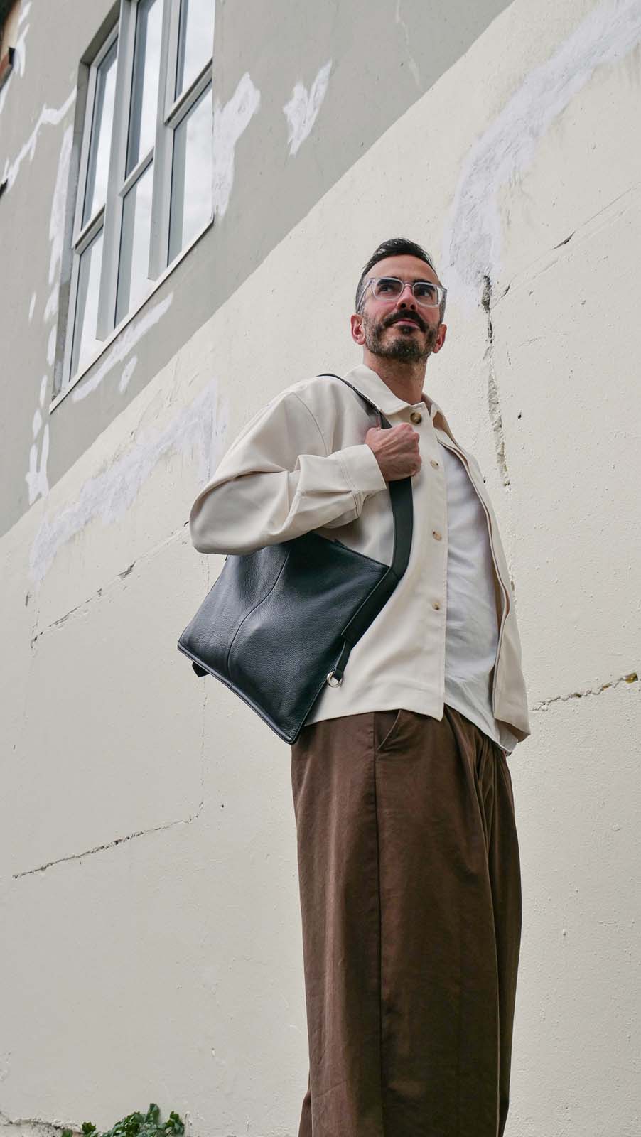 Man wearing the medium Kite Bag in black on one shoulder