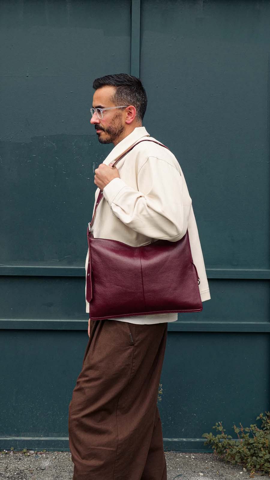 Man wearing medium burgundy Kite Bag on one shoulder