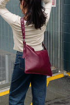 Person wearing a burgundy bag crossbody in an urban setting