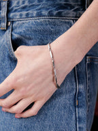 Person wearing a silver bracelet on a denim background