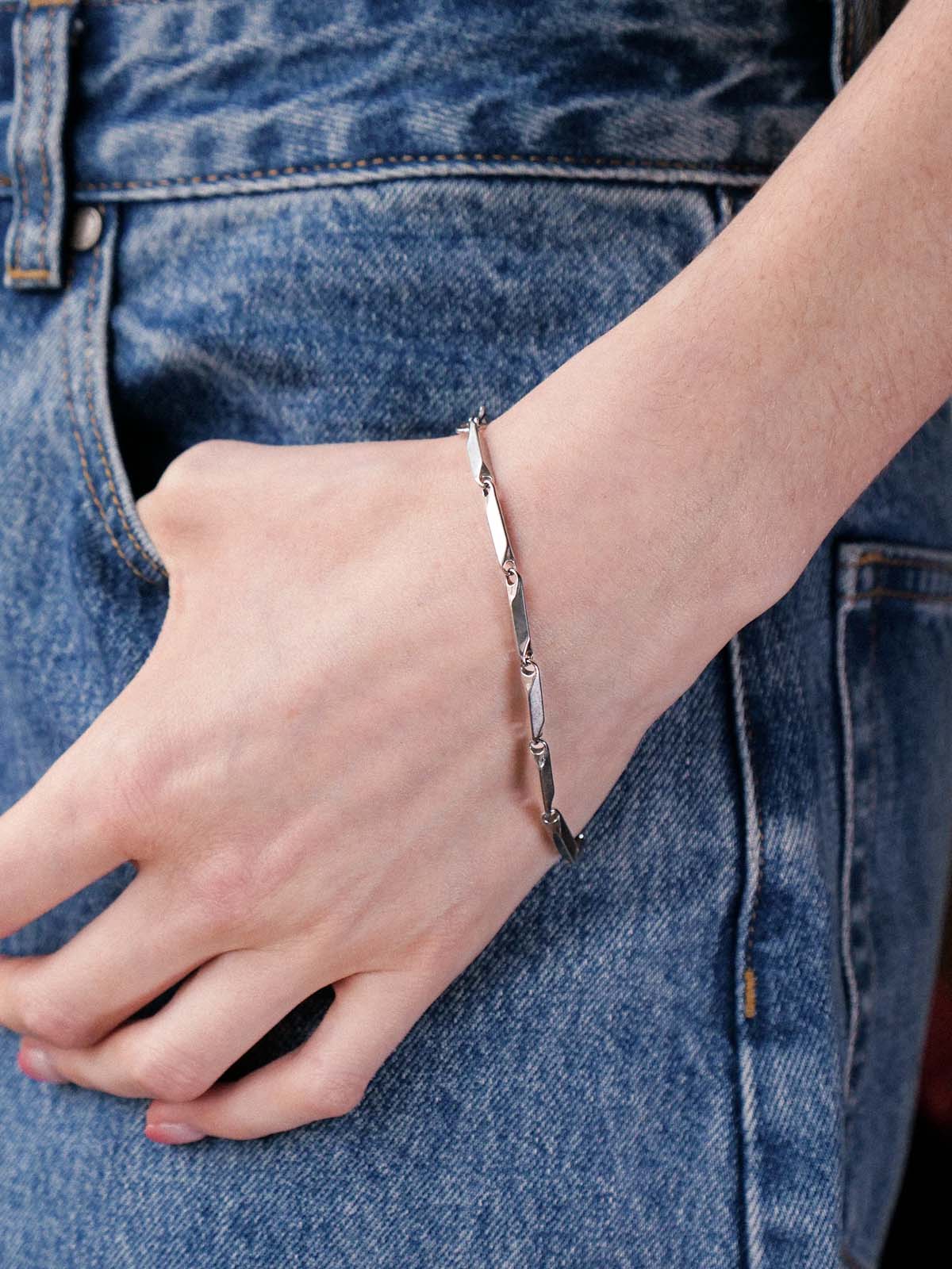 Person wearing a silver bracelet on a denim background