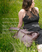 Sage crossbody bag brown genuine leather sitting next to model on grass field