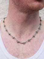 Silver chain necklace worn by a person with a neutral background
