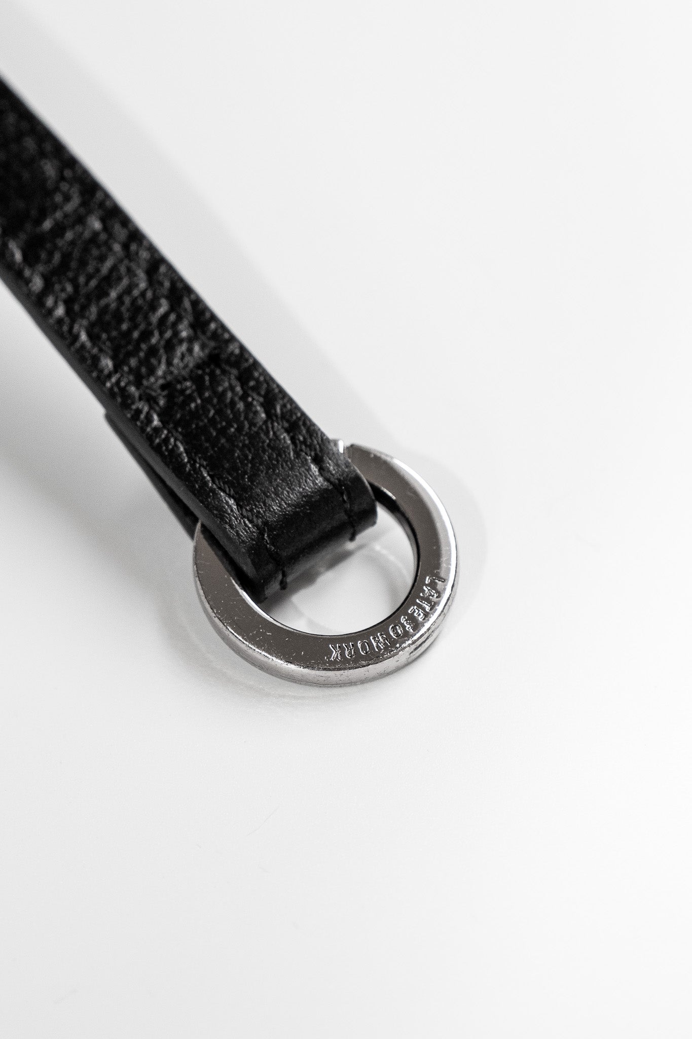 Close up of silver ring hardware on the end of one Willow Bag strap featuring 'Late to Work' embossed on the ring
