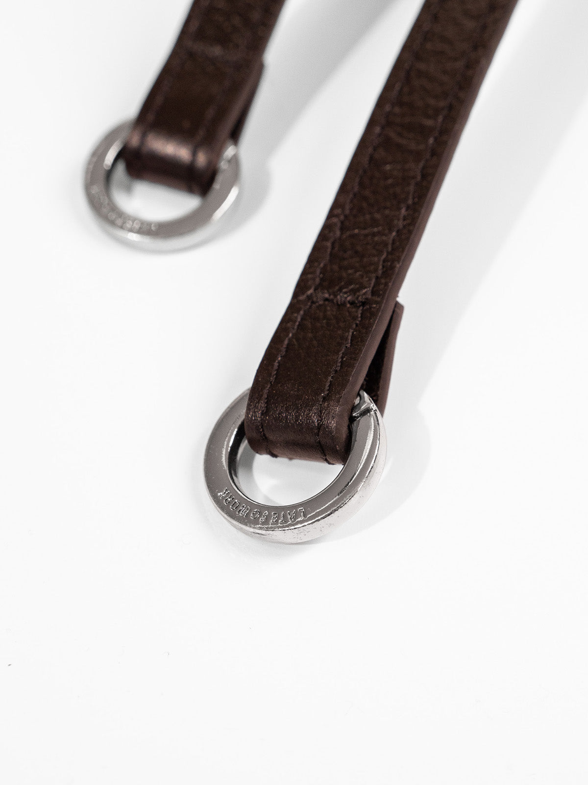 Close up of silver ring hardware on the end of Willow Bag strap featuring 'Late to Work' embossed on the ring