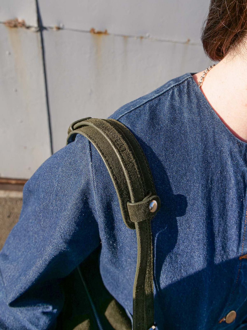 Close up of the forest suede Willow Bag on a shoulder with the matching shoulder pad attached.