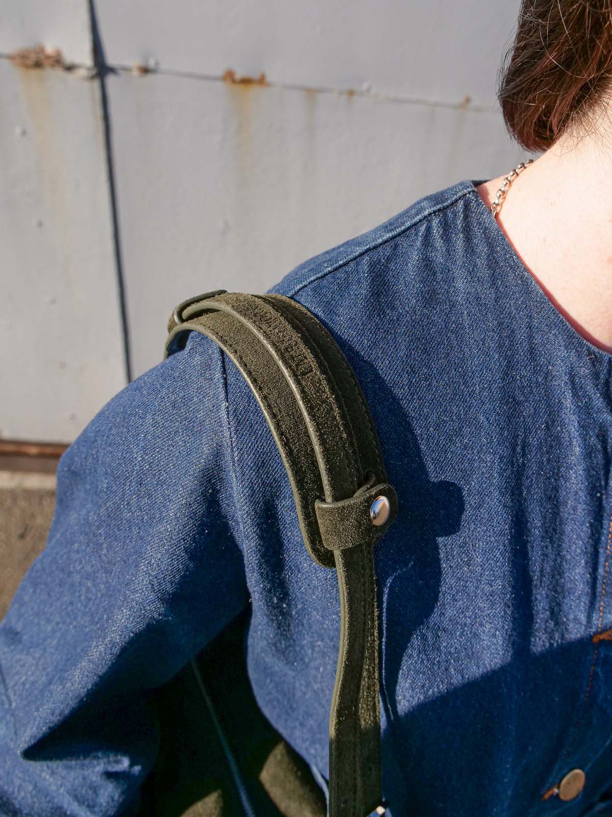 Close up of the forest suede Willow Bag on a shoulder with the matching shoulder pad attached.
